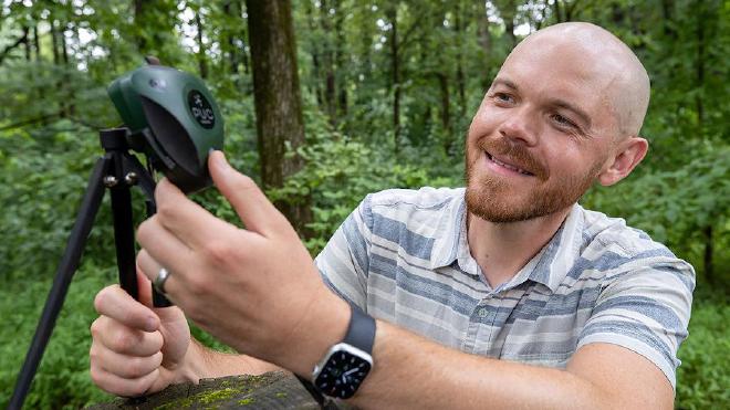 Brent Pease, profesor adjunto de la Facultad de Silvicultura y Horticultura de la SIU Carbondale, muestra el BirdWeather PUC, un dispositivo resistente a la intemperie con micrófonos, wifi, GPS, sensores ambientales e inteligencia artificial. La investigación de Pease es un ejemplo del trabajo que convierte a la SIU Carbondale en una universidad de Investigación 1. Crédito de la imagen: Russell Bailey